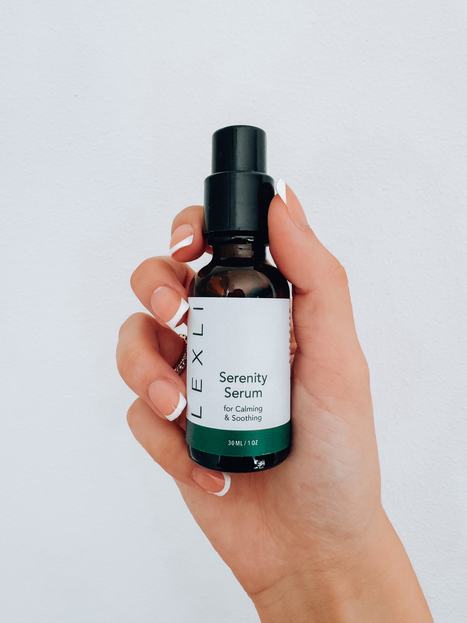 Photo of a hand holding a 1 ounce bottle of Lexli Serenity Serum, a calming serum for face.
