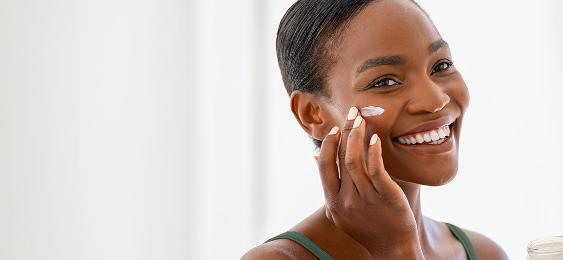 woman smiling and applying moisturizer to her cheek