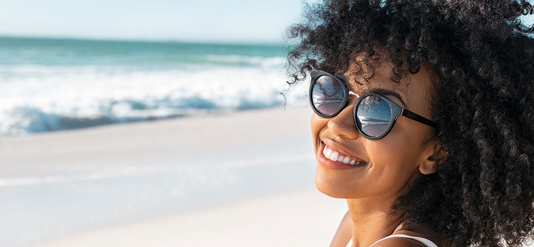 woman with sunglasses smiling on the beach