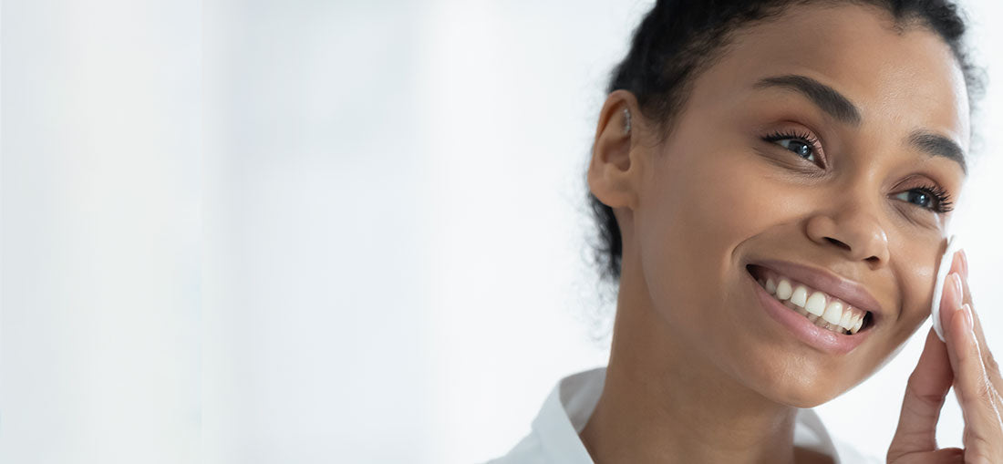 smiling woman removing toner from her face with a cotton round