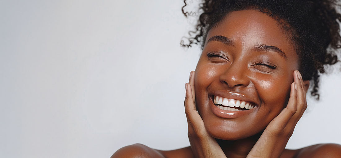 woman with glowing skin smiling and touching her cheeks